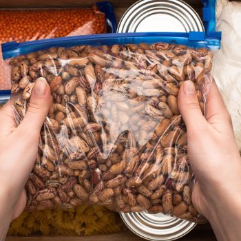 cropped view of woman holding  beans in zipper bag, food donation concept